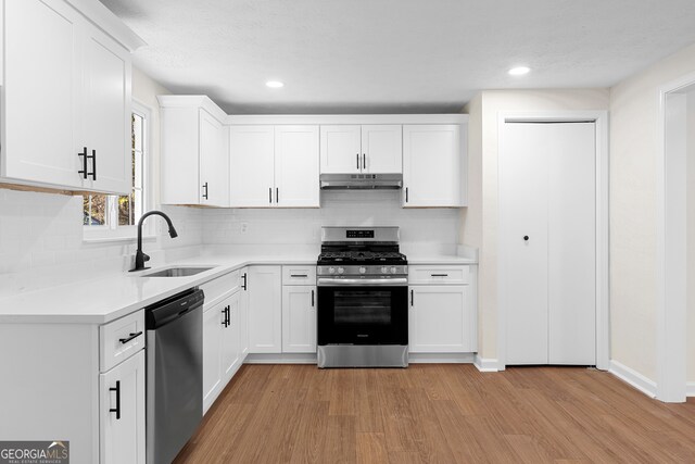 kitchen with light wood-type flooring, white cabinetry, sink, and appliances with stainless steel finishes