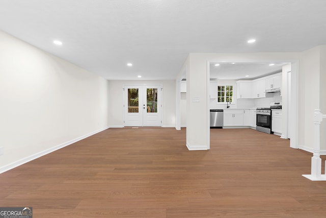 unfurnished living room with french doors, light wood-type flooring, and sink