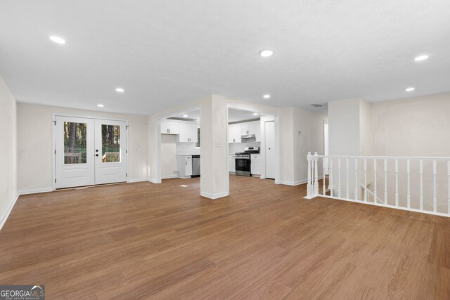 unfurnished living room featuring french doors and light hardwood / wood-style floors