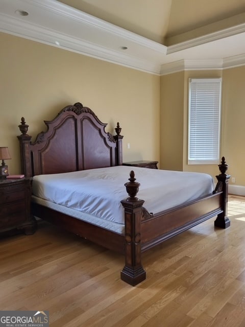 bedroom featuring crown molding, lofted ceiling, and light wood-type flooring