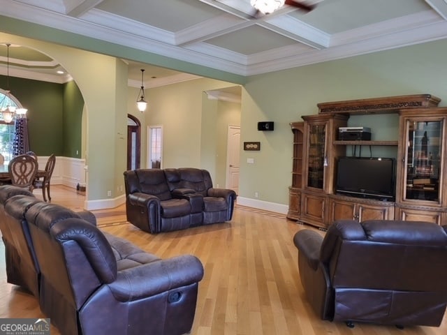 living room with beam ceiling, crown molding, light hardwood / wood-style flooring, and coffered ceiling