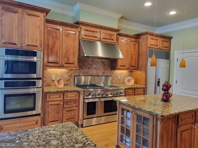 kitchen with light stone countertops, premium appliances, light hardwood / wood-style flooring, and crown molding