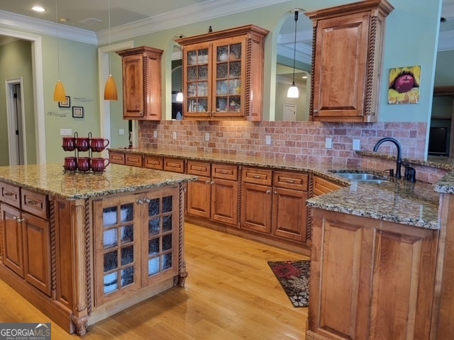 kitchen featuring stone counters, decorative backsplash, light hardwood / wood-style floors, and sink