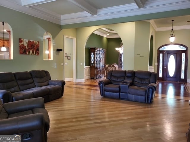 living room featuring hardwood / wood-style floors, coffered ceiling, crown molding, beamed ceiling, and a notable chandelier