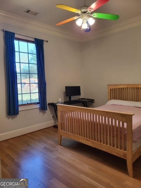 bedroom featuring hardwood / wood-style flooring, ceiling fan, and crown molding