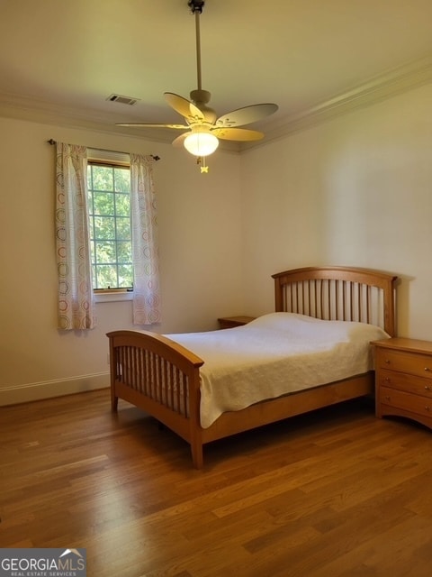 bedroom featuring hardwood / wood-style floors, ceiling fan, and crown molding