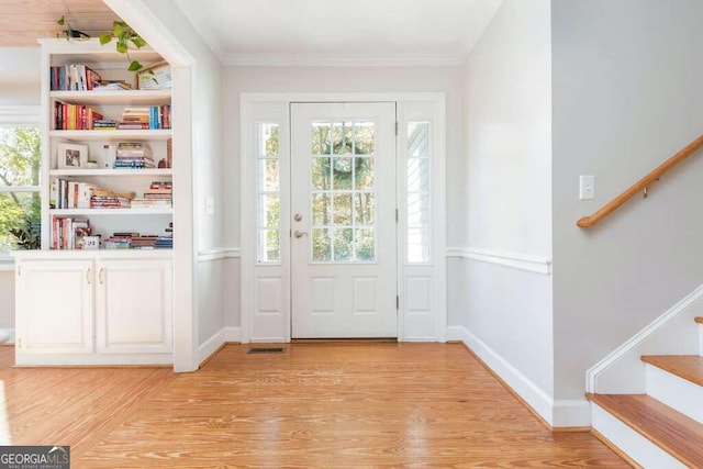 doorway to outside featuring crown molding and light hardwood / wood-style flooring