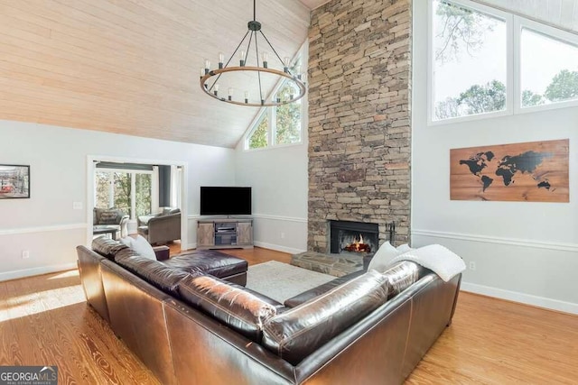 living room with high vaulted ceiling, a stone fireplace, and plenty of natural light