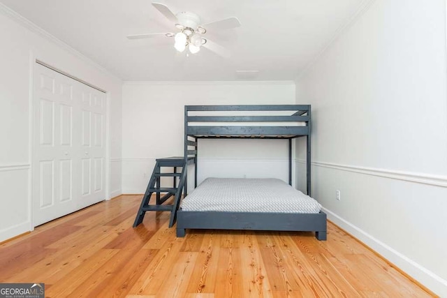 bedroom with ceiling fan, a closet, wood-type flooring, and ornamental molding