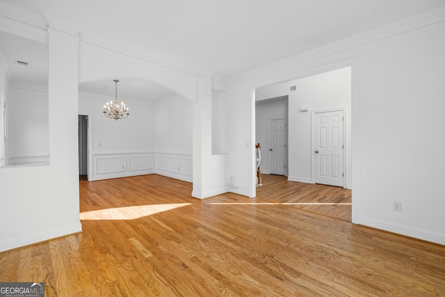 unfurnished room with ornamental molding, hardwood / wood-style floors, and a chandelier