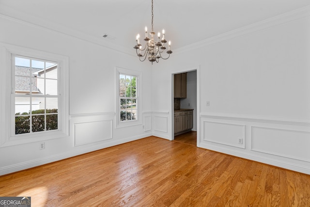 unfurnished dining area with crown molding, a notable chandelier, and light hardwood / wood-style floors