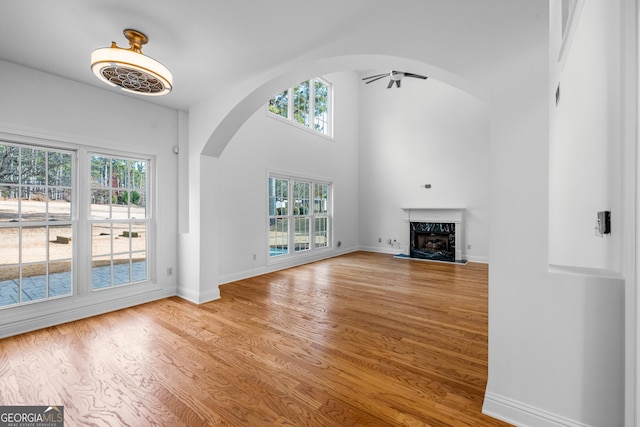 unfurnished living room featuring hardwood / wood-style floors, a towering ceiling, and a premium fireplace