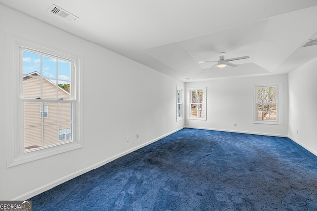 unfurnished room with ceiling fan, a raised ceiling, and dark carpet