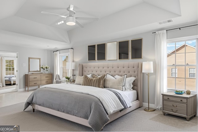 carpeted bedroom featuring ceiling fan, lofted ceiling, a raised ceiling, and multiple windows