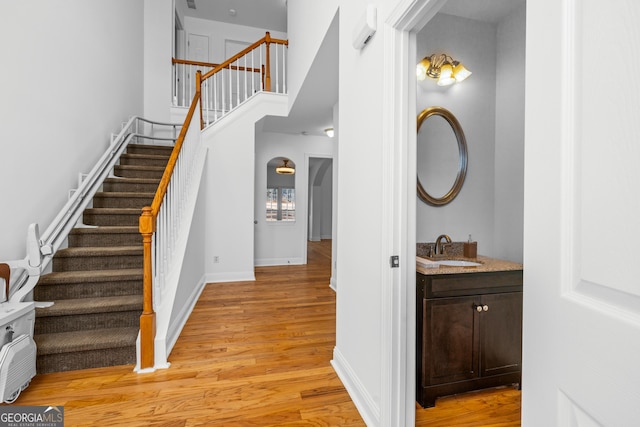 stairway featuring sink, a towering ceiling, and wood-type flooring