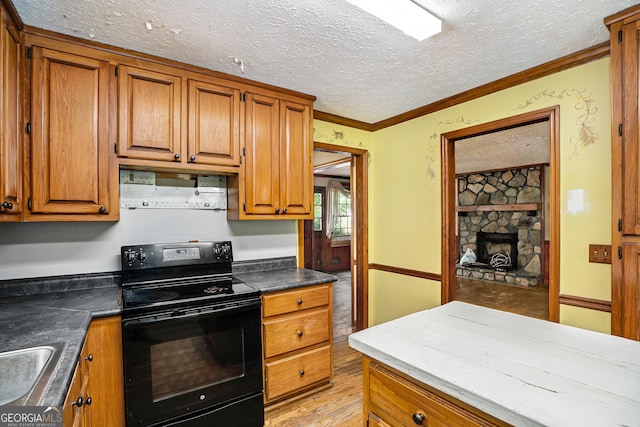 kitchen featuring a textured ceiling, crown molding, electric range, light hardwood / wood-style flooring, and a fireplace