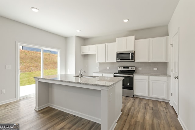 kitchen with white cabinets, a center island with sink, sink, dark hardwood / wood-style floors, and appliances with stainless steel finishes