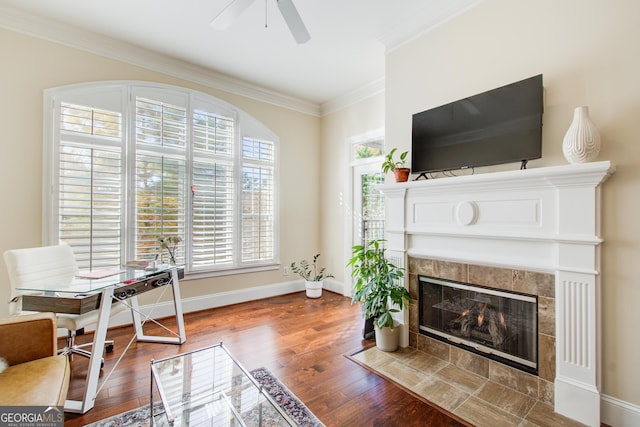 living room featuring a tiled fireplace, ceiling fan, hardwood / wood-style floors, and ornamental molding