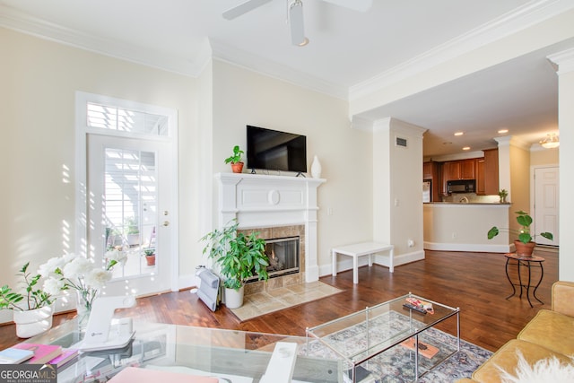 living room featuring a fireplace, hardwood / wood-style floors, ceiling fan, and ornamental molding