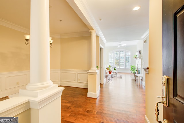 entryway featuring ceiling fan, wood-type flooring, crown molding, and decorative columns