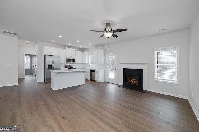 kitchen with ceiling fan, a center island, appliances with stainless steel finishes, white cabinets, and hardwood / wood-style flooring