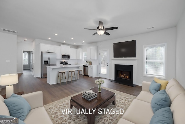 living room with ceiling fan and dark wood-type flooring