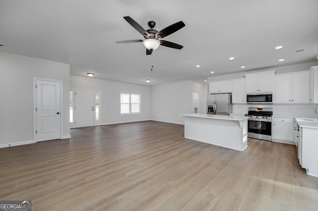 kitchen featuring white cabinetry, a center island, ceiling fan, stainless steel appliances, and light wood-type flooring