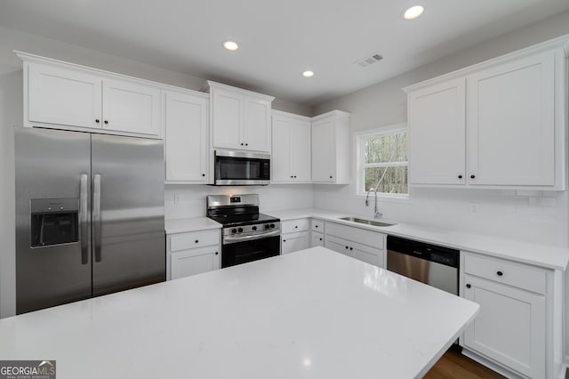 kitchen with decorative backsplash, appliances with stainless steel finishes, white cabinetry, and sink