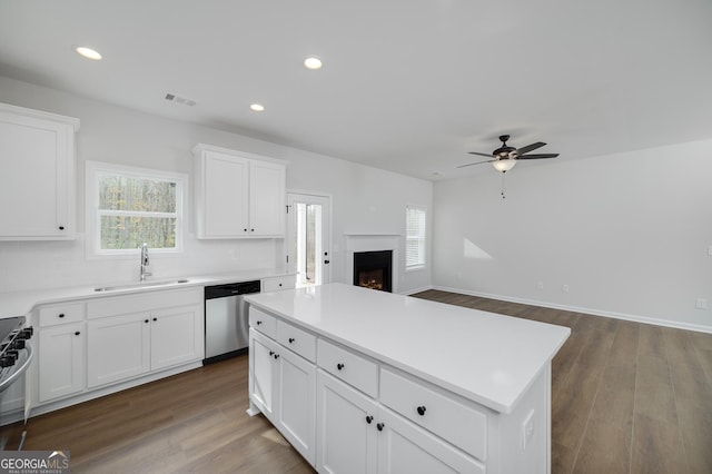 kitchen with stainless steel appliances, sink, hardwood / wood-style flooring, white cabinets, and a center island