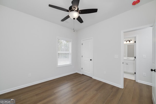 unfurnished bedroom featuring connected bathroom, ceiling fan, and dark wood-type flooring