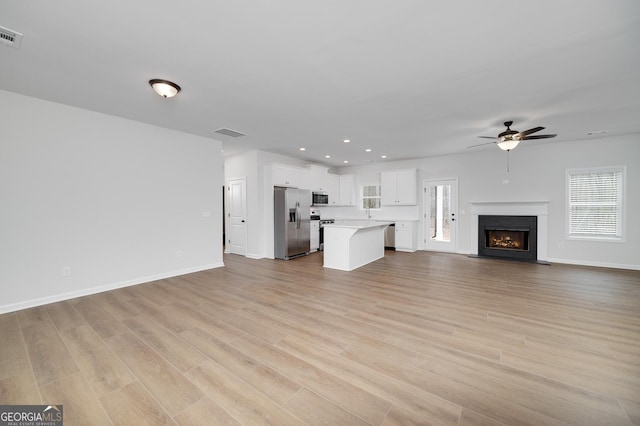 unfurnished living room featuring ceiling fan and light hardwood / wood-style flooring