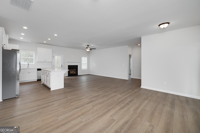 unfurnished living room with ceiling fan, light wood-type flooring, and sink