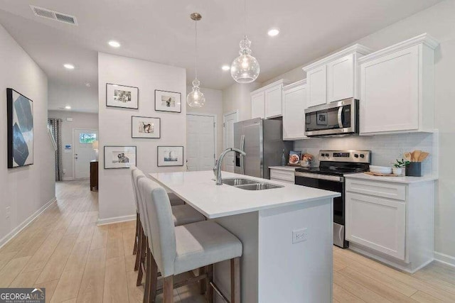 kitchen featuring white cabinetry, sink, a center island with sink, and appliances with stainless steel finishes