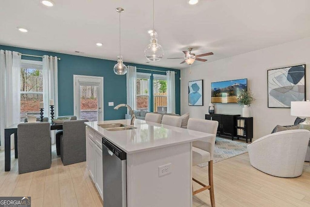 kitchen featuring a healthy amount of sunlight, a center island with sink, stainless steel dishwasher, and sink