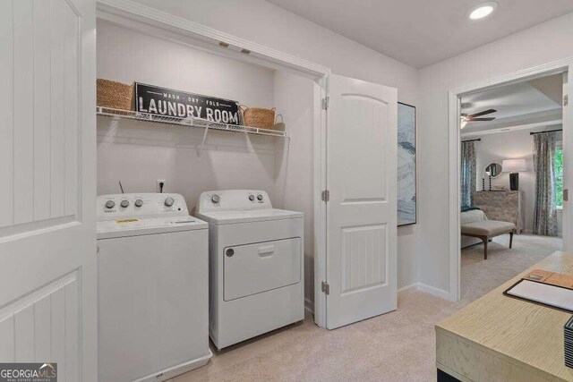 laundry area featuring light carpet, ceiling fan, and washing machine and clothes dryer