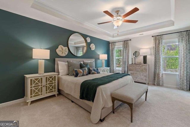 carpeted bedroom featuring a raised ceiling, multiple windows, and ceiling fan