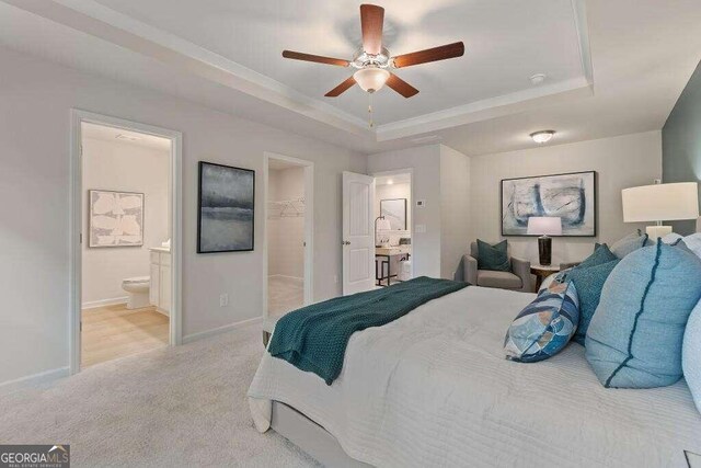 bedroom featuring a tray ceiling, ensuite bathroom, a closet, and a spacious closet