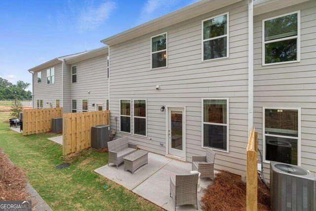 rear view of house featuring a patio area, central air condition unit, and a yard