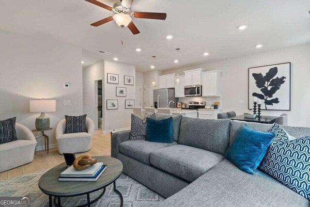 living room featuring ceiling fan and light hardwood / wood-style flooring