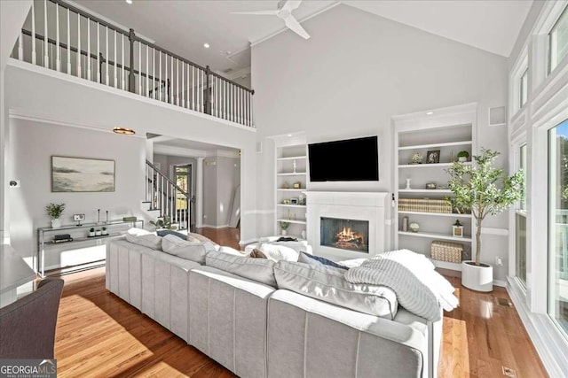 living room with a wealth of natural light, high vaulted ceiling, and light hardwood / wood-style floors