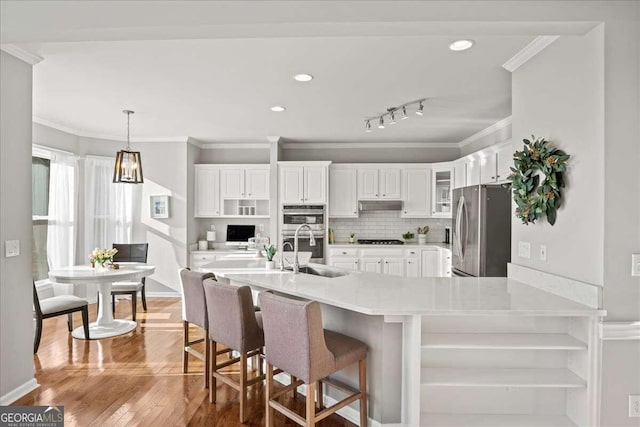 kitchen with appliances with stainless steel finishes, a breakfast bar, sink, light hardwood / wood-style floors, and white cabinetry