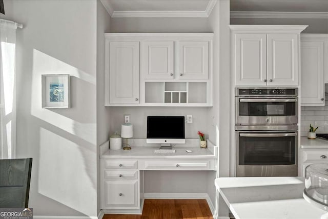 kitchen with backsplash, double oven, crown molding, hardwood / wood-style floors, and white cabinetry