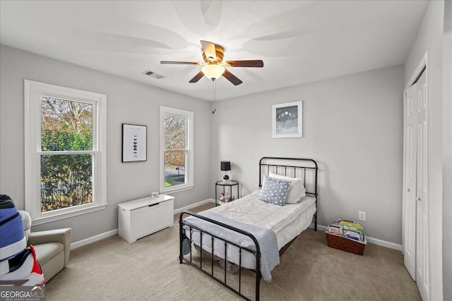 bedroom featuring ceiling fan, light carpet, and a closet