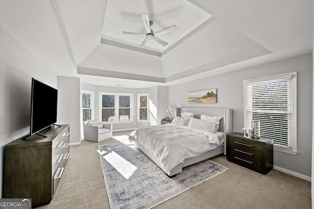 carpeted bedroom featuring a raised ceiling, multiple windows, and ceiling fan