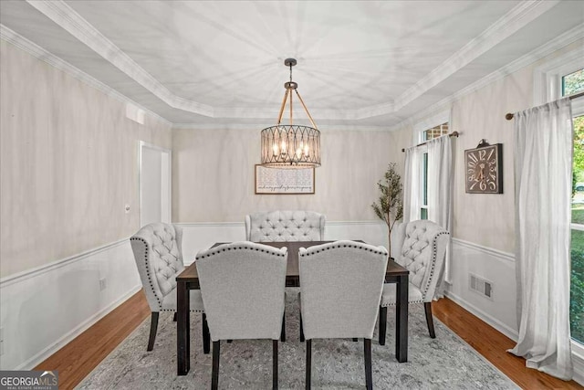 dining area with a chandelier, hardwood / wood-style floors, a tray ceiling, and crown molding