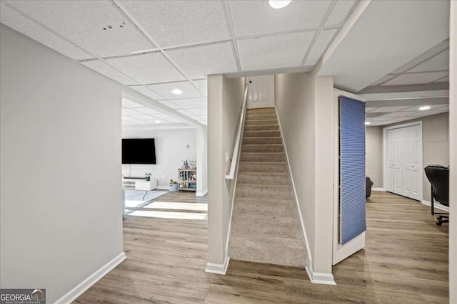 stairs featuring a drop ceiling and wood-type flooring