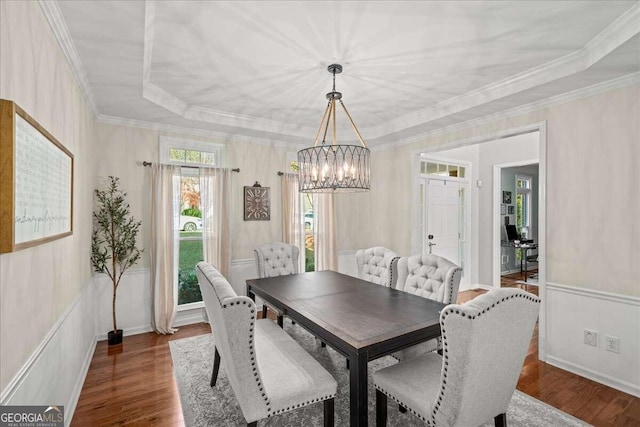 dining area featuring a tray ceiling, dark hardwood / wood-style flooring, ornamental molding, and an inviting chandelier