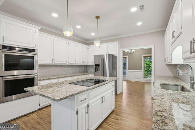 kitchen with sink, stainless steel appliances, light hardwood / wood-style floors, decorative light fixtures, and white cabinets