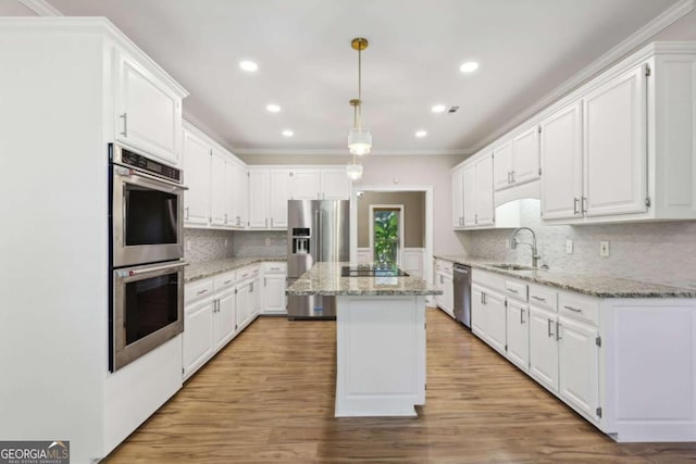 kitchen with white cabinets, hanging light fixtures, sink, appliances with stainless steel finishes, and a kitchen island