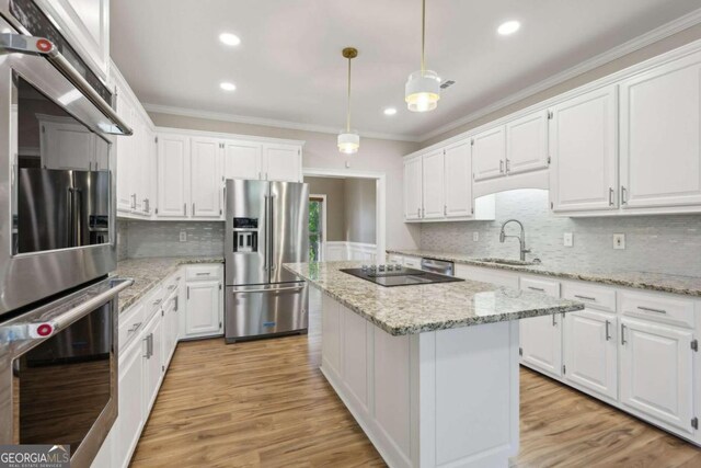 kitchen with a center island, white cabinets, decorative light fixtures, and appliances with stainless steel finishes